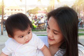 Portrait of happy Asian mother and daughter. Asian woman and little toddler girl in the playground park. Happy family playing together at playground park