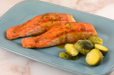 Salmon fish fillets with white wine sauce and brussel sprouts on blue serving platter