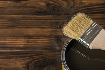 Brush on a tin with tinting composition on a wooden background. - obrazy, fototapety, plakaty
