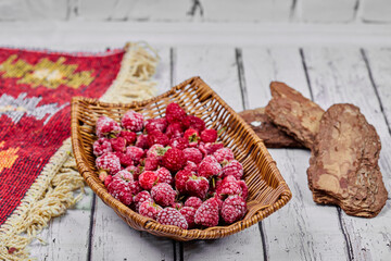 Healthy fresh raspberries in wooden basket with carved rug