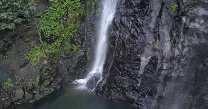 Water Cascade On The Cliff. Mainapi Waterfall At Cotigao Wildlife Sanctuary In Netravali, South Goa, India. aerial tilt down