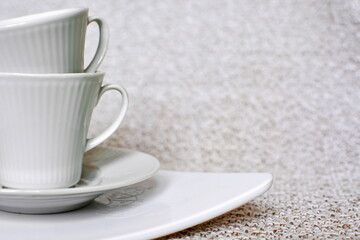 white porcelain coffee cups in stack on white tray on cloth close up