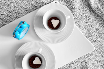 pair of coffee cups with instant coffee and piece of refined sugar in shape of heart on bottom and...