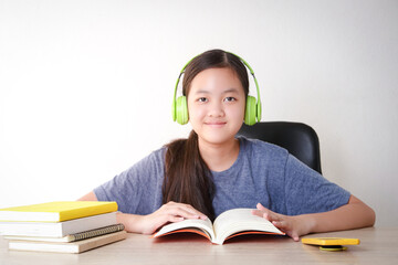 Asian female students learn online from home. Put on headphones and read a book. Concept of social distance Use of technology for education. - Powered by Adobe