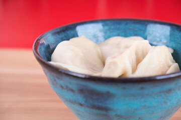 A bowl of dumplings in front of the red background