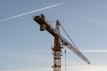 Imposing Tower Crane, Behind It Blue Evening Sky With Contrails