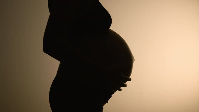 Beautiful SILHOUETTED CLOSEUP of a very pregnant belly close to giving birth