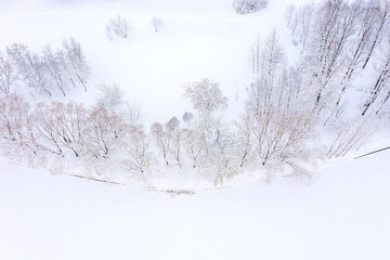aerial top view of winter landscape with frozen river and bare trees on riverbank