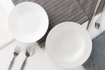 White empty plates set on the table with knives and forks and tablecloths. Ready to eat