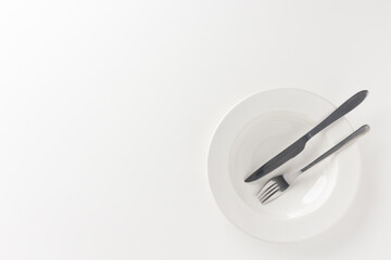 The empty white plates were set on the table with knives and forks. Ready to eat