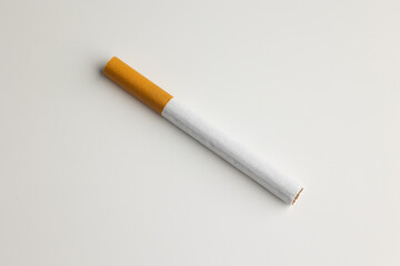 A cigarette is placed on a white table. Take a photo in the studio