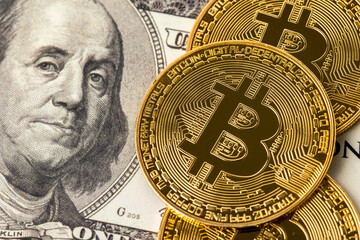 Bitcoin cryptocurrency on hundred us dollars. Close up electronic golden coin. Business and financial concept.
