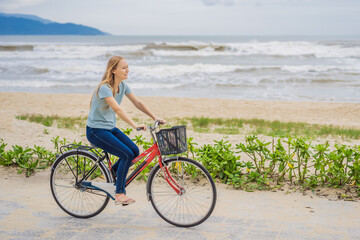 Fototapeta premium Young woman with bicycle enjoying a bike ride by the sea