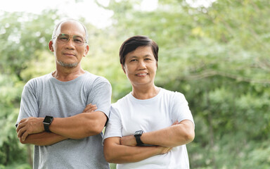 Asian Senior Couple with arms crossed smiling relaxing in park.