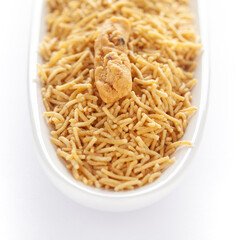 Indian spicy snacks (Namkeen) - Bikaneri Besan Bhujia in a white oval-shaped plate, made with chickpea flour (Besan), side view, against the white background.