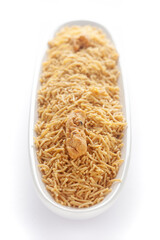 Indian spicy snacks (Namkeen) - Bikaneri Besan Bhujia in a white oval-shaped plate, made with chickpea flour (Besan), side view, against the white background.