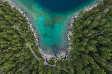 Aerial overhead drone shot of pathway through forests by Eibseelake in Germany summer