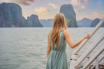 Fototapeta premium Attractive woman in a dress is traveling by boat in Halong Bay. Vietnam. Travel to Asia, happiness emotion, summer holiday concept. Picturesque sea landscape. Ha Long Bay, Vietnam