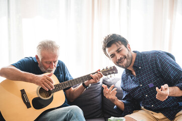 old man playing guitar with grandchild at home, family concept