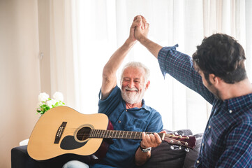 old man playing guitar with grandchild at home, family concept