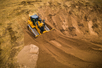 A bull dozer pushed sand into a large pile.