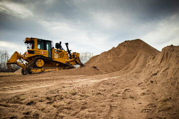 A yellow bulldozer pushes a full load of material into a pile.