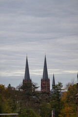 Fototapeta premium Freiburg im Breisgau, Germany - 11 01 2012: The spires of the Church against the grey sky. Empty european street on the cloudy autumn day