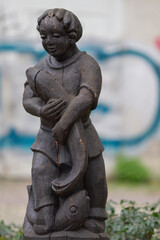 Fototapeta na wymiar Freiburg im Breisgau, Germany - 11 01 2012: wooden statue of a boy with a fish in the park outdoors