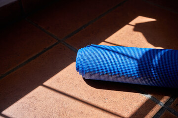 Sports background, blue yoga mat lying on th floor ready to pick up