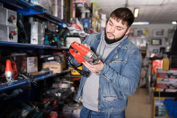 Attentive man buys jigsaw in tools store