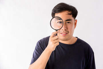 Fototapeta na wymiar Man holding magnifying glass on white background. man with a magnifying glass in studio. Positive curious man in casual wear looking at through magnifier 