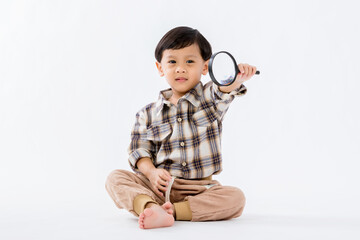 Child holding magnifying glass on white background. Boy with a magnifying glass in studio. 