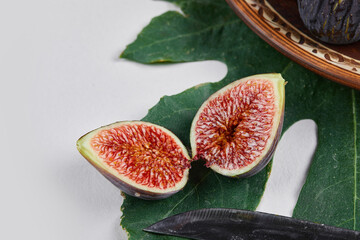A purple figs with red seeds on a green leaf