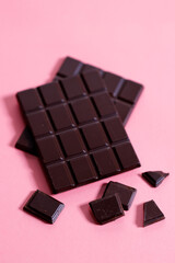 Dark chocolate bars on pink background.