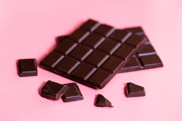 Dark chocolate bars on pink background.