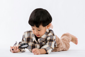Fototapeta na wymiar Child holding magnifying glass on white background. Boy with a magnifying glass in studio. Positive curious boy in casual wear looking at through magnifier 
