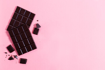 Dark chocolate bars on pink background, top view.