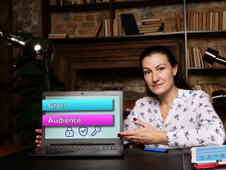 Conceptual photo about Gross Audience with written phrase. Cheerful young businesswoman working at...