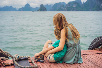 Fototapeta na wymiar Mom and son travelers is traveling by boat in Halong Bay. Vietnam. Travel to Asia, happiness emotion, summer holiday concept. Traveling with children concept. After COVID 19. Picturesque sea landscape