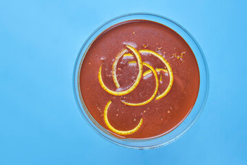 Chocolate cocktail with lemon slices in tall glass over pastel blue background.