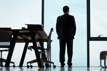 rear view of asian businessman looking out of window in office