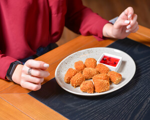 Fried camembert cheese in breading with cranberry sauce served on a white plate. Still life, eating out concept.