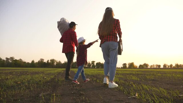 Farmer and happy family. Senior farmer in wheat field with box of vegetables. Happy family in field at sunset. Senior farmer with his family is harvesting. Happy family hiking. Farmer checks the crop