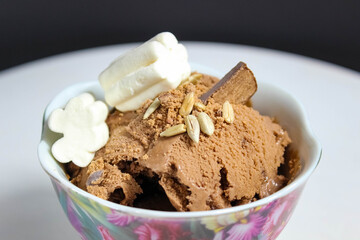 Chocolate ice cream in a bowl, decorated with marshmallows, seeds and chocolate chips.