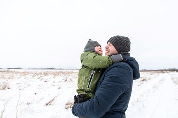 Fototapeta na wymiar Happy moments of the son and father walking in the winter in the field. Family lifestyle.