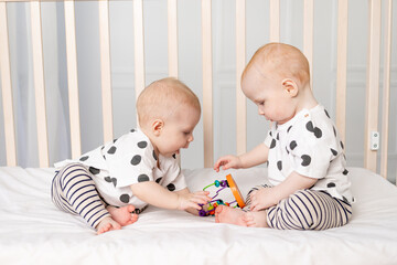 two twin babies play in the crib, the concept of the relationship of children of brother and...