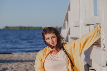 Nice plus size girl leans on wooden structure on beach
