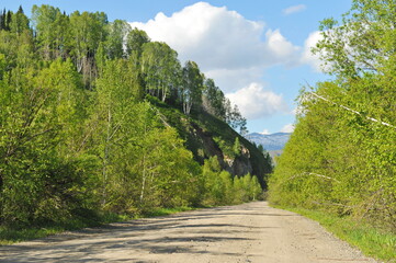 Ridder, Kazakhstan - 06.05.2013 : A road laid along a mountainous and hilly area with trees, shrubs...
