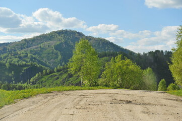 Ridder, Kazakhstan - 06.05.2013 : A road laid along a mountainous and hilly area with trees, shrubs...