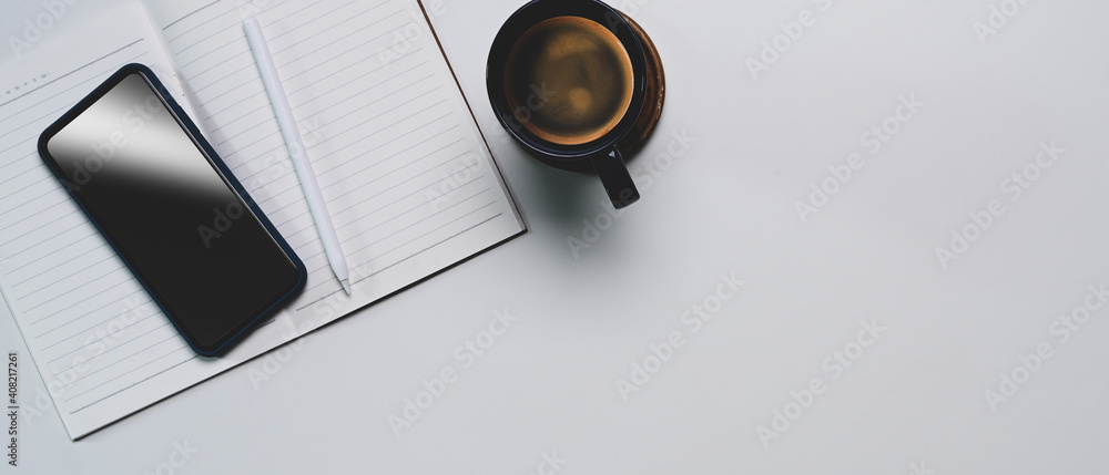 Poster top view of mock up smart phone, empty notebook, coffee cup and copy space on white table.